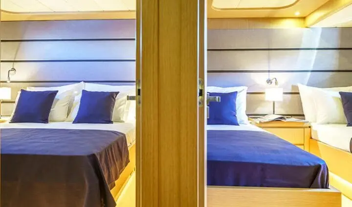Phantom yacht cabin interior with double bed, blue pillows, and wood framing