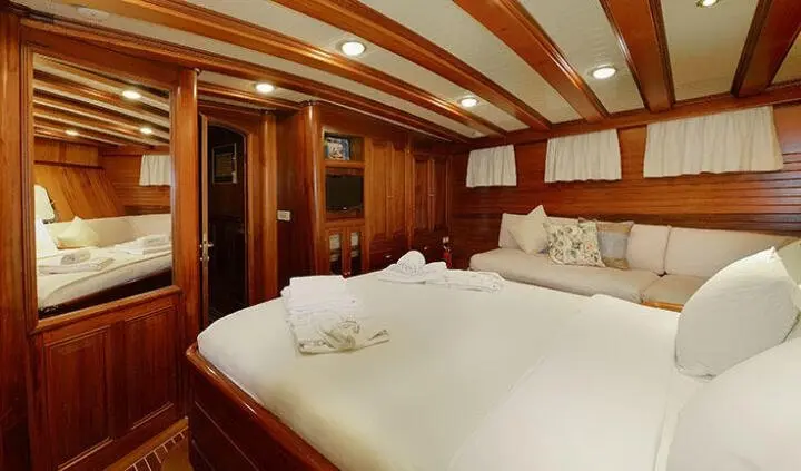 Ecce Navigo master cabin with a large bed, white linens, and wood-panelled walls