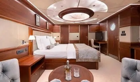 Lady Gita cabin interior with two beds, wooden panels, round ceiling light