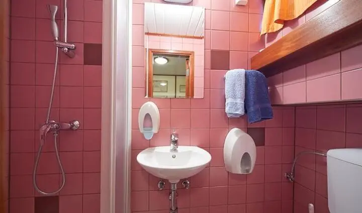 Small pink-tiled bathroom aboard Altair yacht, sink, mirror, towel, and toilet visible