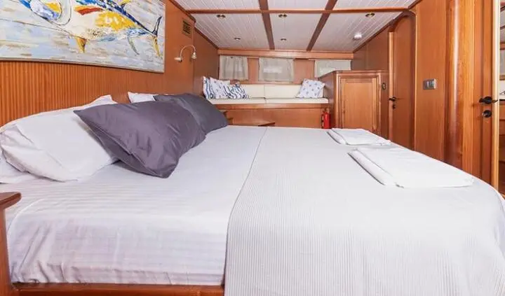 Two white beds with wooden headboard and navy throw pillows in a cabin