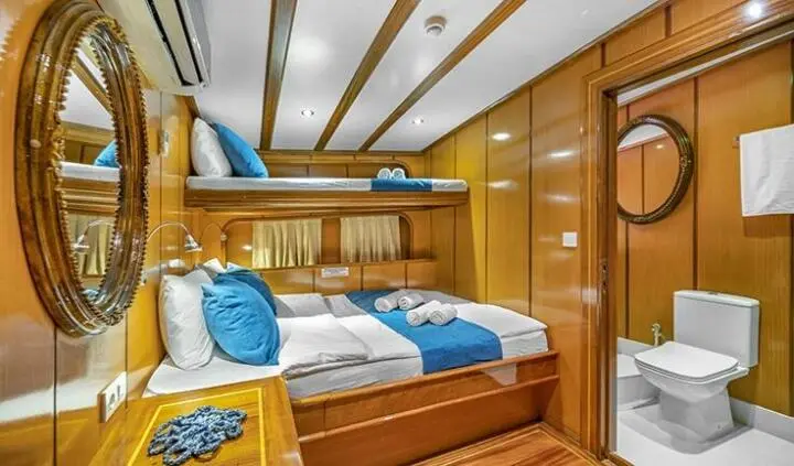 Twin bunk master bedroom on a yacht with wooden cabinets and blue bedding
