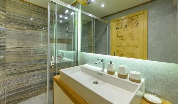 Master cabin with king bed, ensuite bathroom, wood accents, and clean lighting
