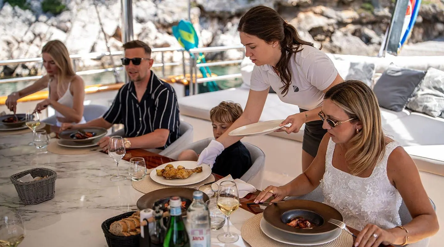 Dalmatino yacht dining scene with people seated around a table on deck
