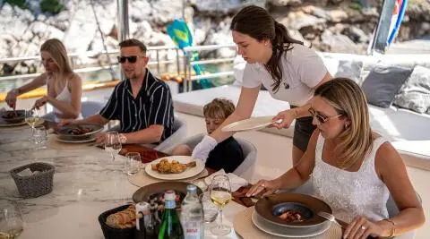 Dalmatino yacht dining scene with people seated around a table on deck