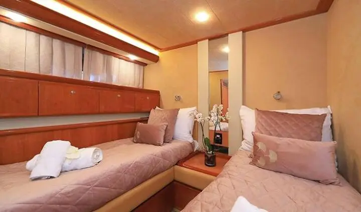 Twin-berth cabin on Quo Vadis I yacht with beige upholstery and wooden panels