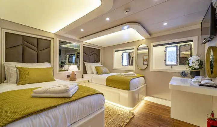 Queen Of Makri cabin with twin beds under warm lighting and wood accents