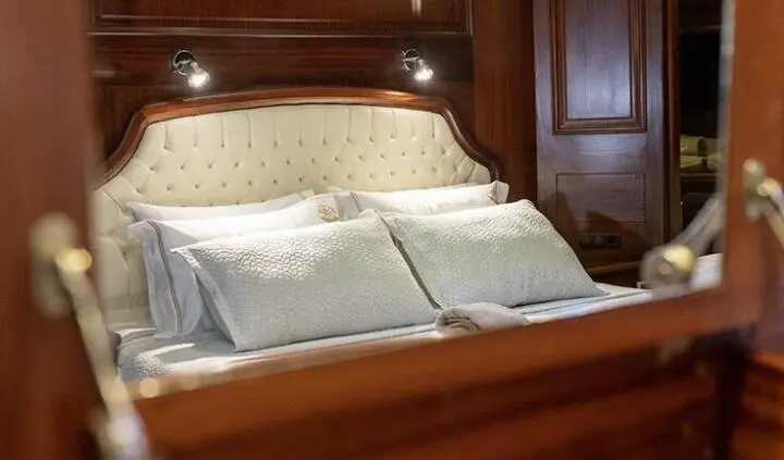 Master cabin with king bed, tufted headboard and white bedding, wooden walls