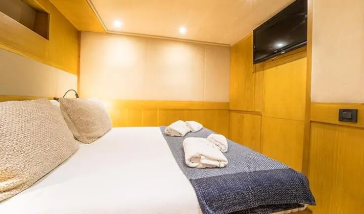 Cozy cabin with two beds, wood-paneled walls, soft lighting, and folded towels