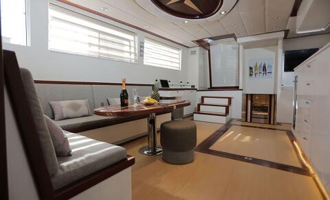 Gulet Grand Sailor interior salon with a round wooden table, champagne bottle and fruit