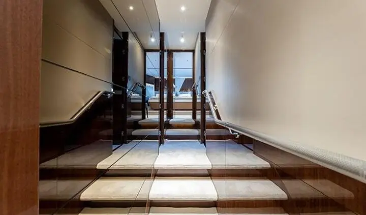 View of a yacht cabin entrance with wooden steps and glass door panels