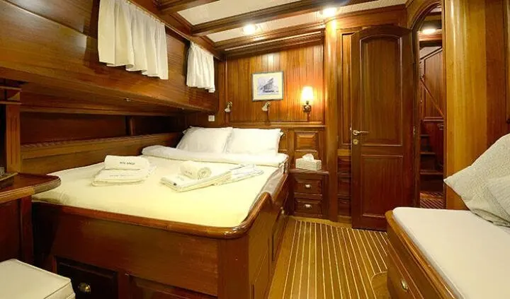 Ecce Navigo cabin with wooden bed, overhead cabinets, warm lighting