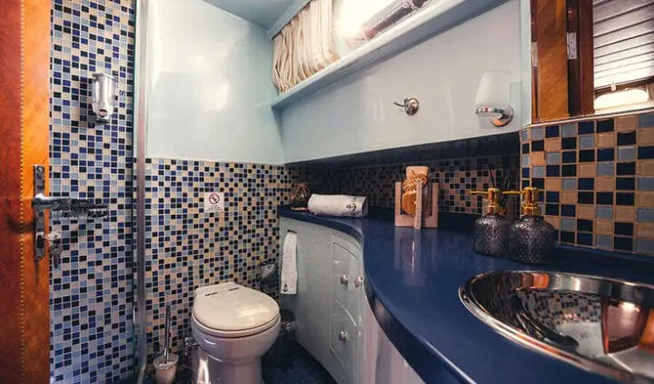 Yacht cabin bathroom with patterned tile and blue cabinetry, compact space