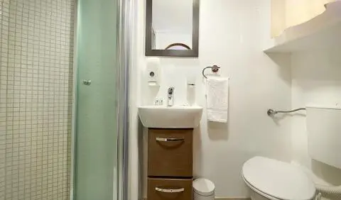 Small bathroom on luxury yacht Linda with sink, mirror, cabinet, and shower door