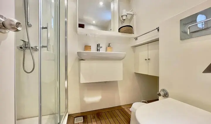 Master cabin with king bed, ensuite bathroom, shelves, and neutral decor