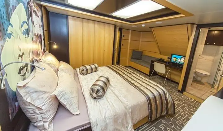 Navilux master cabin with bed and striped linens, wooden panels, soft lighting