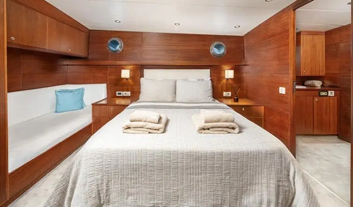 Master cabin with king bed, two nightstands, and ensuite door on wood panel walls