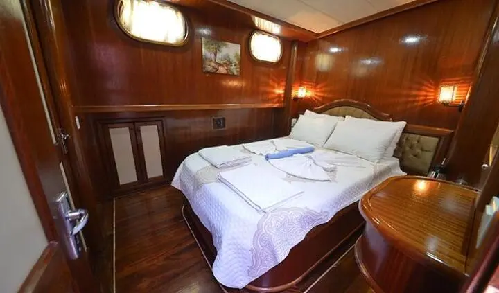 Cozy cabin aboard Prenses Bugce with white bed, wood-paneled walls