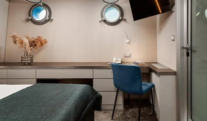 Cabin berth area on Ohana yacht with blue chair and desk against wall