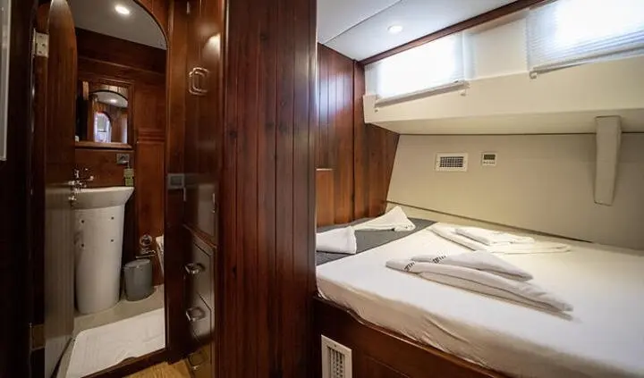 Twin bunk beds with white linens in a wood-paneled cabin on a yacht