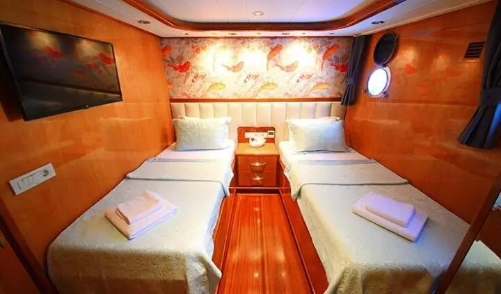 Interior of Maya yacht cabin with two parallel single beds and wooden floor
