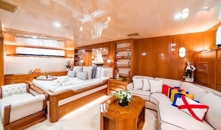 Luxury yacht master cabin with king bed, wood paneling, and seating area