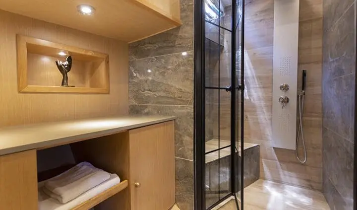 Diva Deniz master cabin ensuite bath with wooden shelves and stone wall