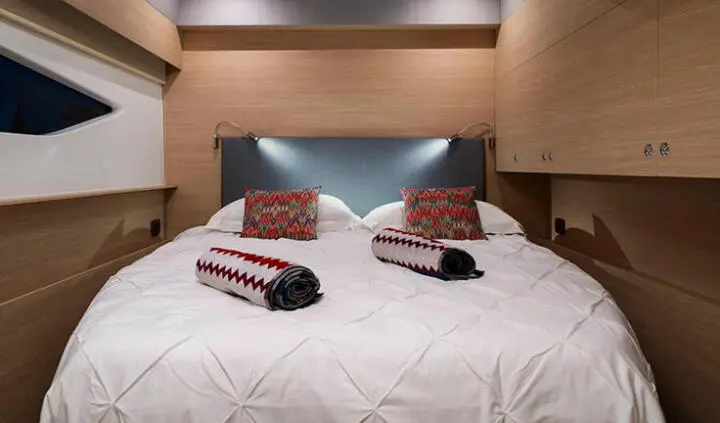 Two neatly made twin beds with white quilted covers and red pillows in a cabin
