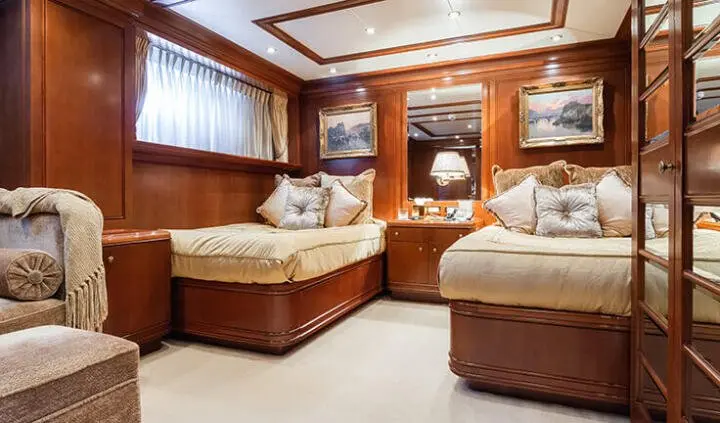 Apogee yacht cabin with two twin beds, rich wood paneling, and plush beige bedding