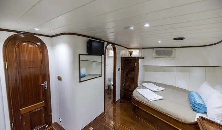 Interior of Faralya yacht cabin with bed, wooden floor, and compact storage