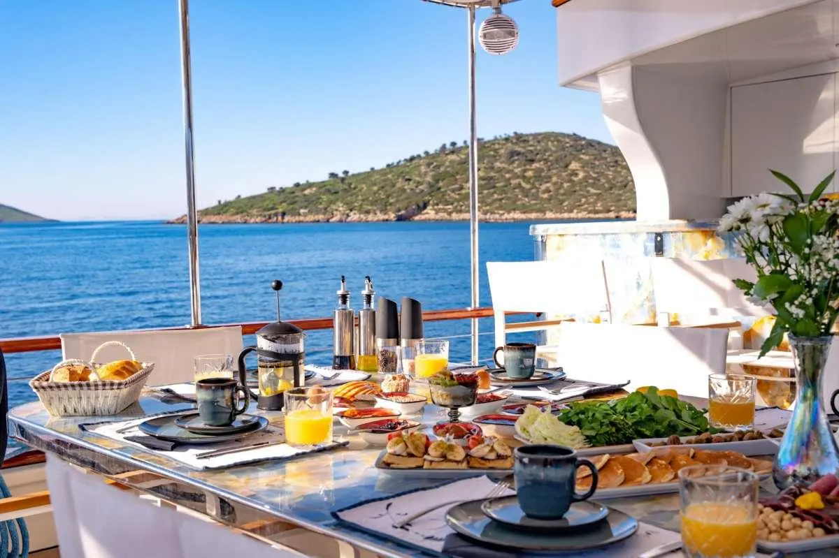Yacht Double Eagle dining setup on deck with ocean and island view