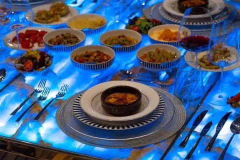 Yacht Double Eagle dining setup with plates and beverages on a blue deck