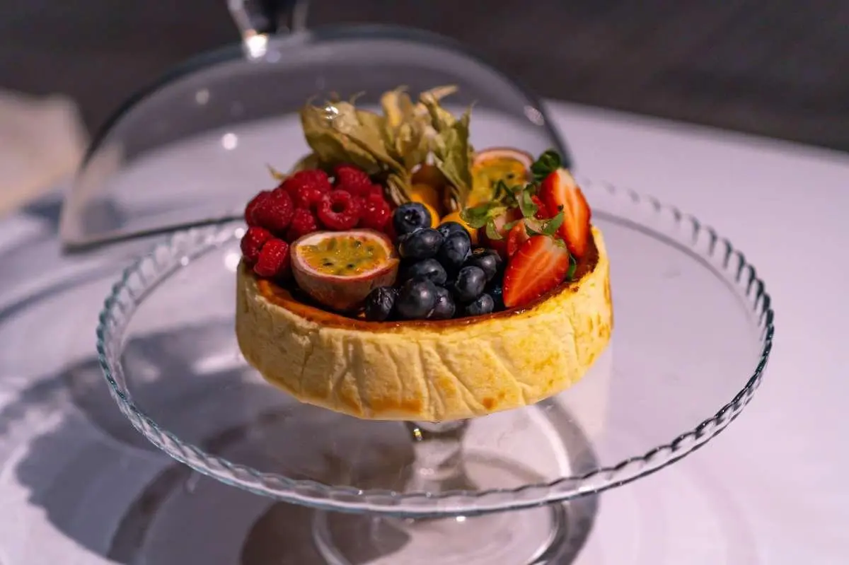 Dessert fruit tart on a glass stand aboard a yacht, Double Eagle, with white table setting