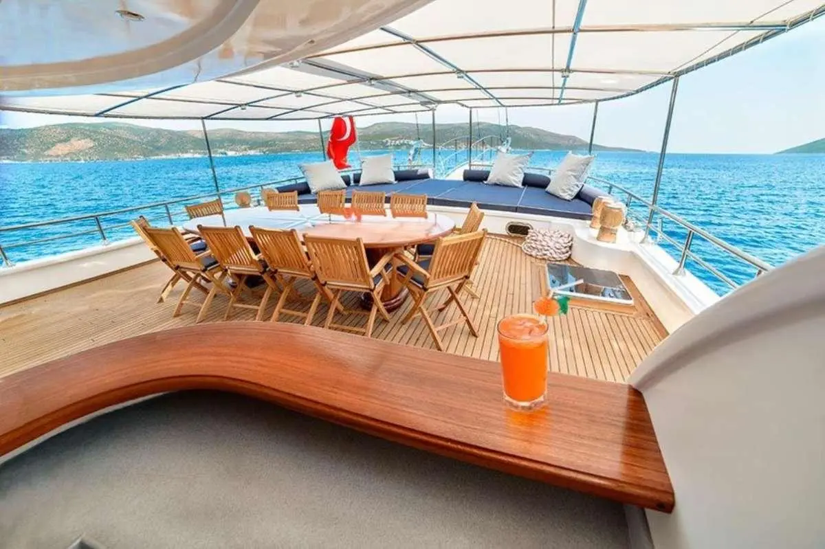 Bella Mare yacht deck with sun loungers, table, and railing overlooking blue sea
