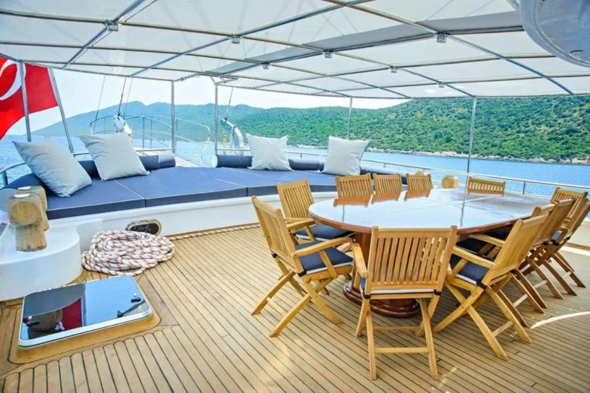 Bella Mare yacht deck with wooden dining table and lounge seating under a canopy