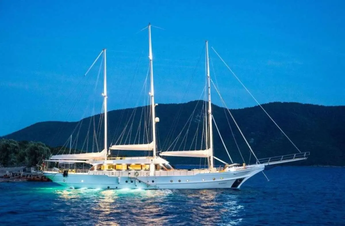 Bella Mare yacht anchored with sails down, calm blue water and hills in background