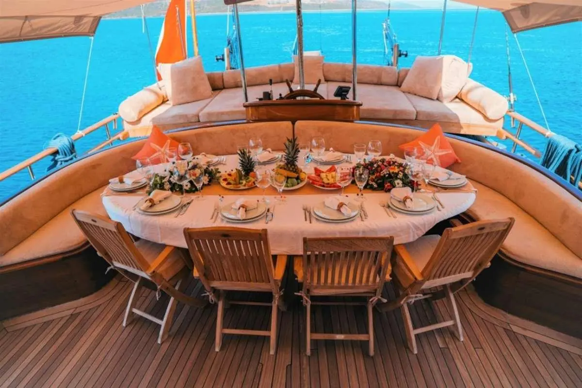 Wicked Felina yacht dining area with round table and beige cushioned seating on deck