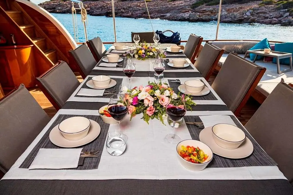 Table set for dining on a yacht with plates, glasses, and flowers