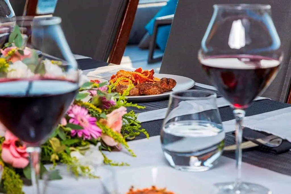 Bodrum Queen yacht table set with flowers, wine glasses, and food plates