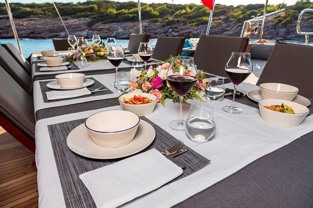 Table setup on deck with drinks, flowers, and place settings aboard Bodrum Queen yacht