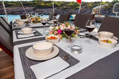 Table setup on deck with drinks, flowers, and place settings aboard Bodrum Queen yacht