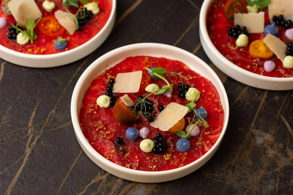 Red fruit smoothie bowls with berries and toppings on a wooden table