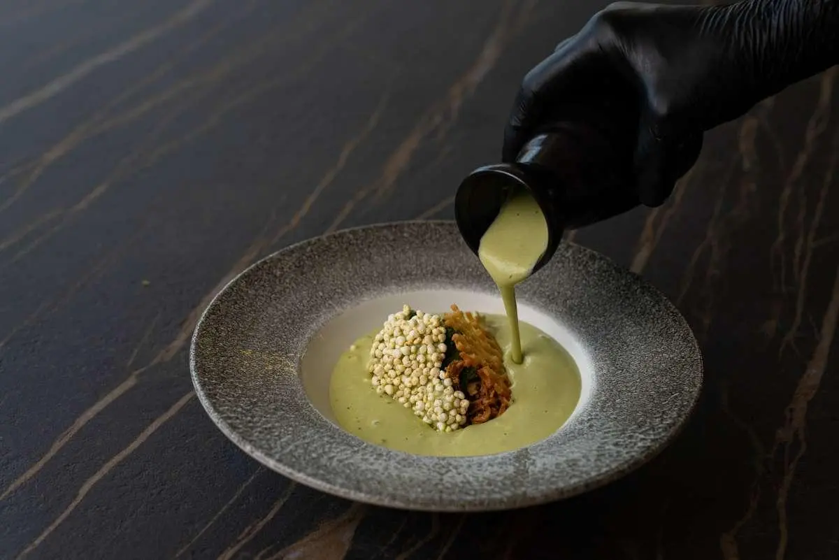 Close-up dish on a gold-toned plate, garnish and lime wedge, dark background