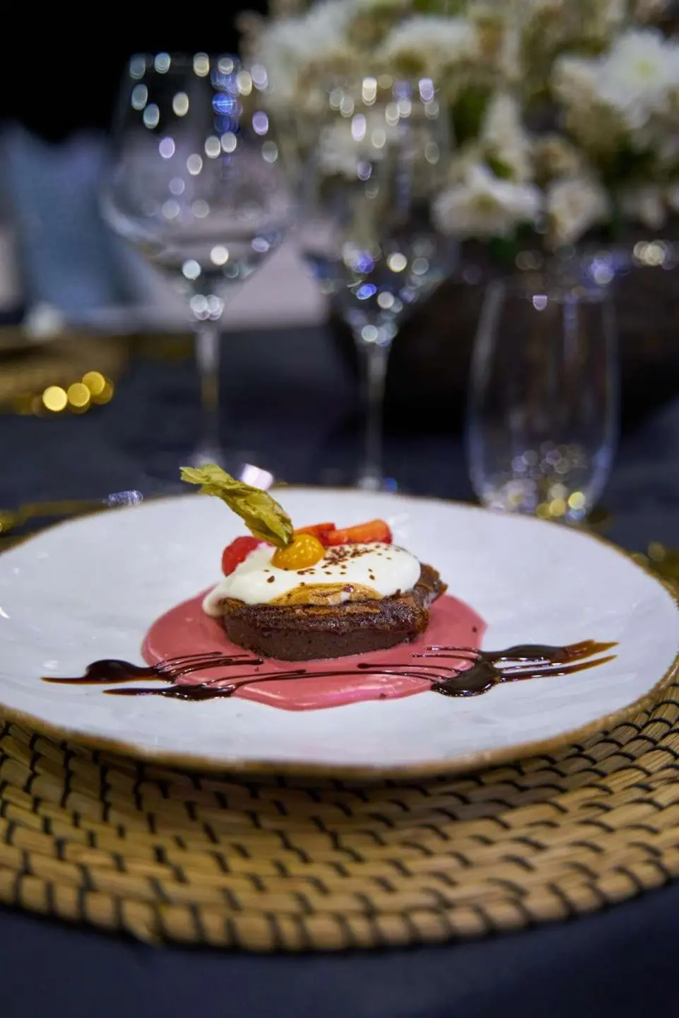 Plate with a small cake or pastry, glassware and table setting on yacht dining table