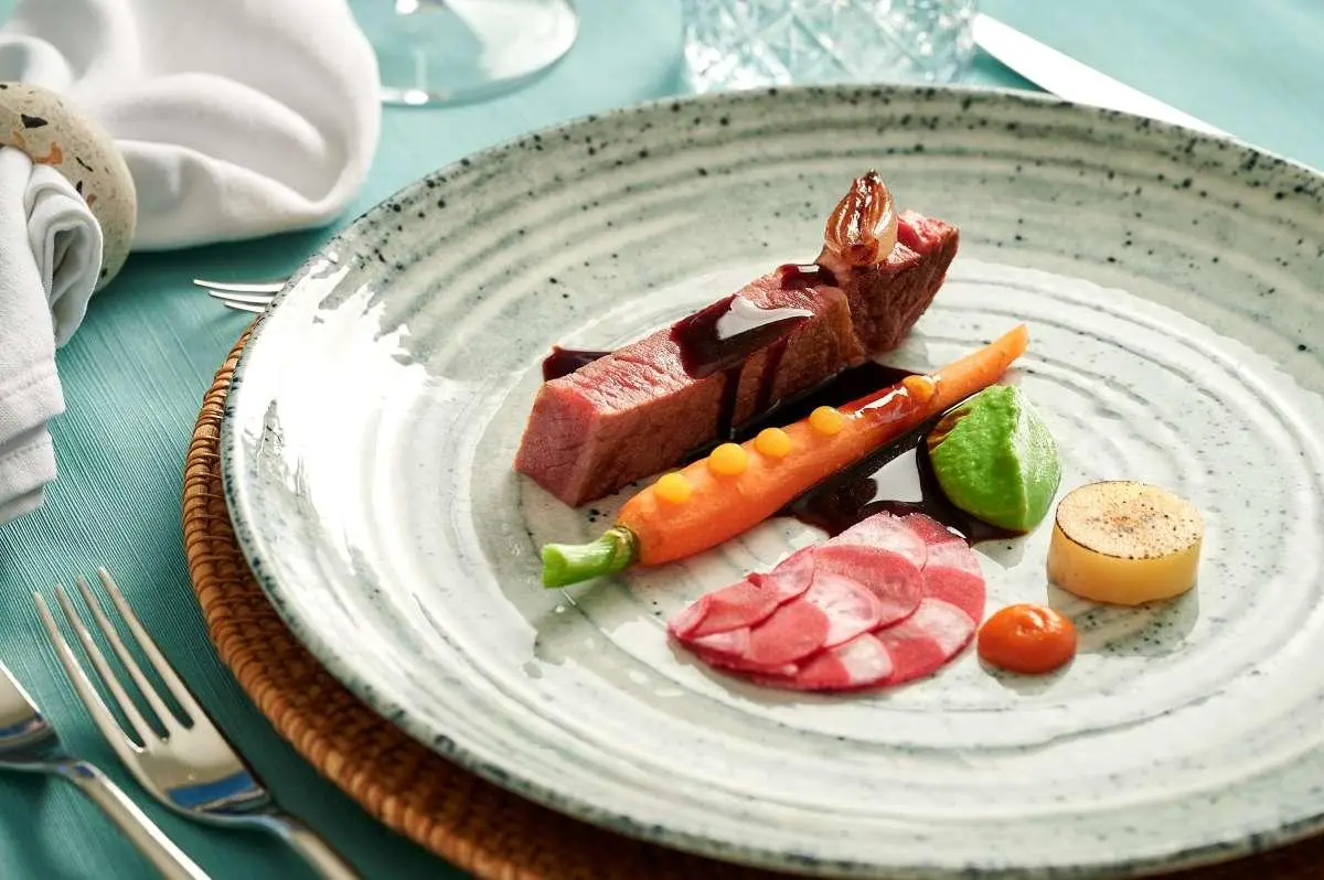 Plate with a chocolate dessert, sliced fruits, and greens on a ceramic dish