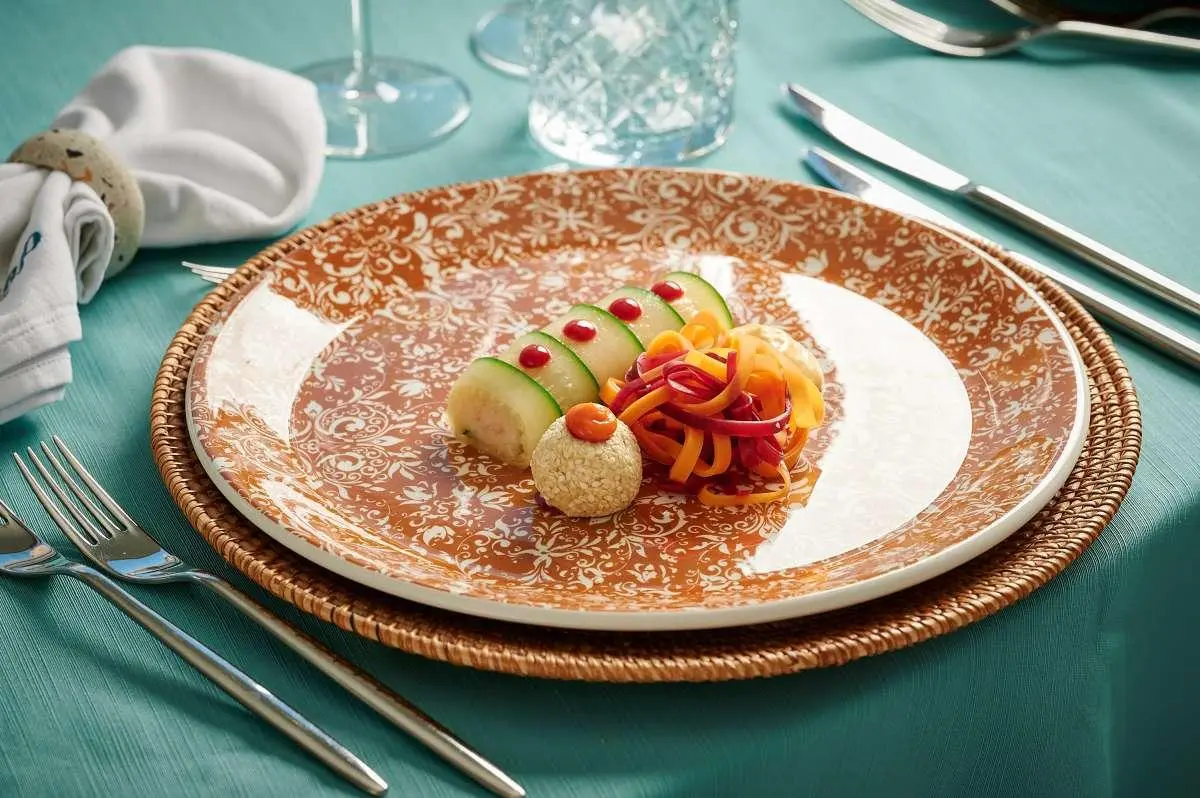 Elegant plated dish on a turquoise table with gold-rimmed plate and cutlery