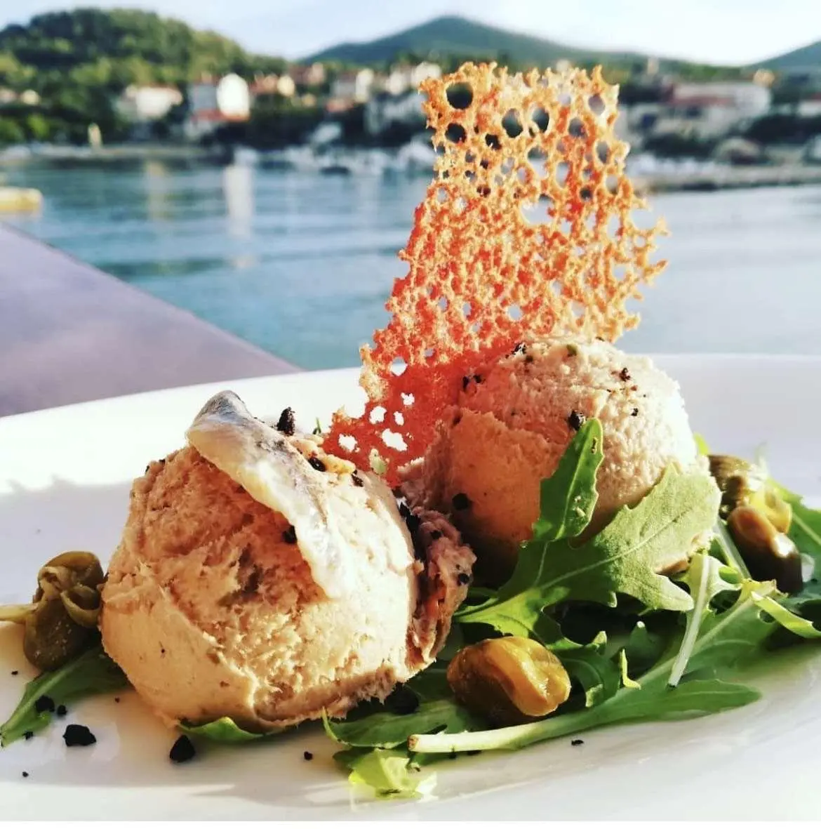 Mendula yacht presented with a plated dessert topped with a garnish aboard a sunny marina