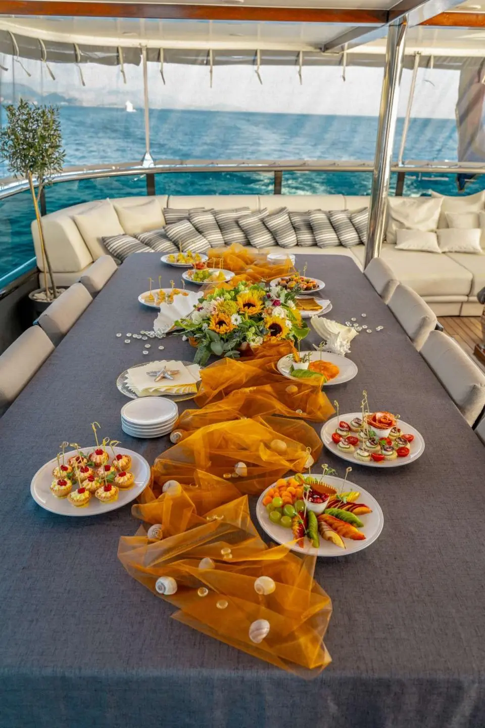 A long dining table on the deck laden with roasted meat and sides aboard a yacht named Freedom