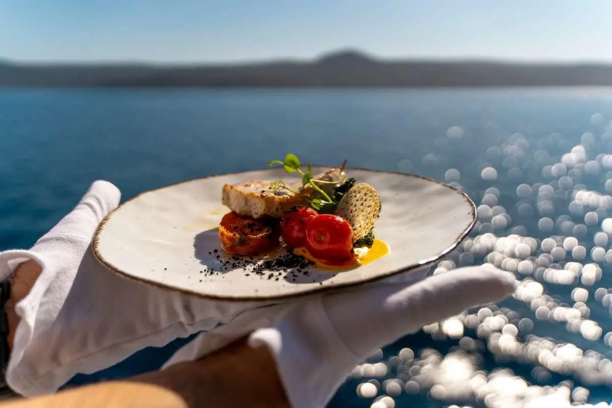 Freshly plated dessert on a yacht deck with blue sea and distant hills