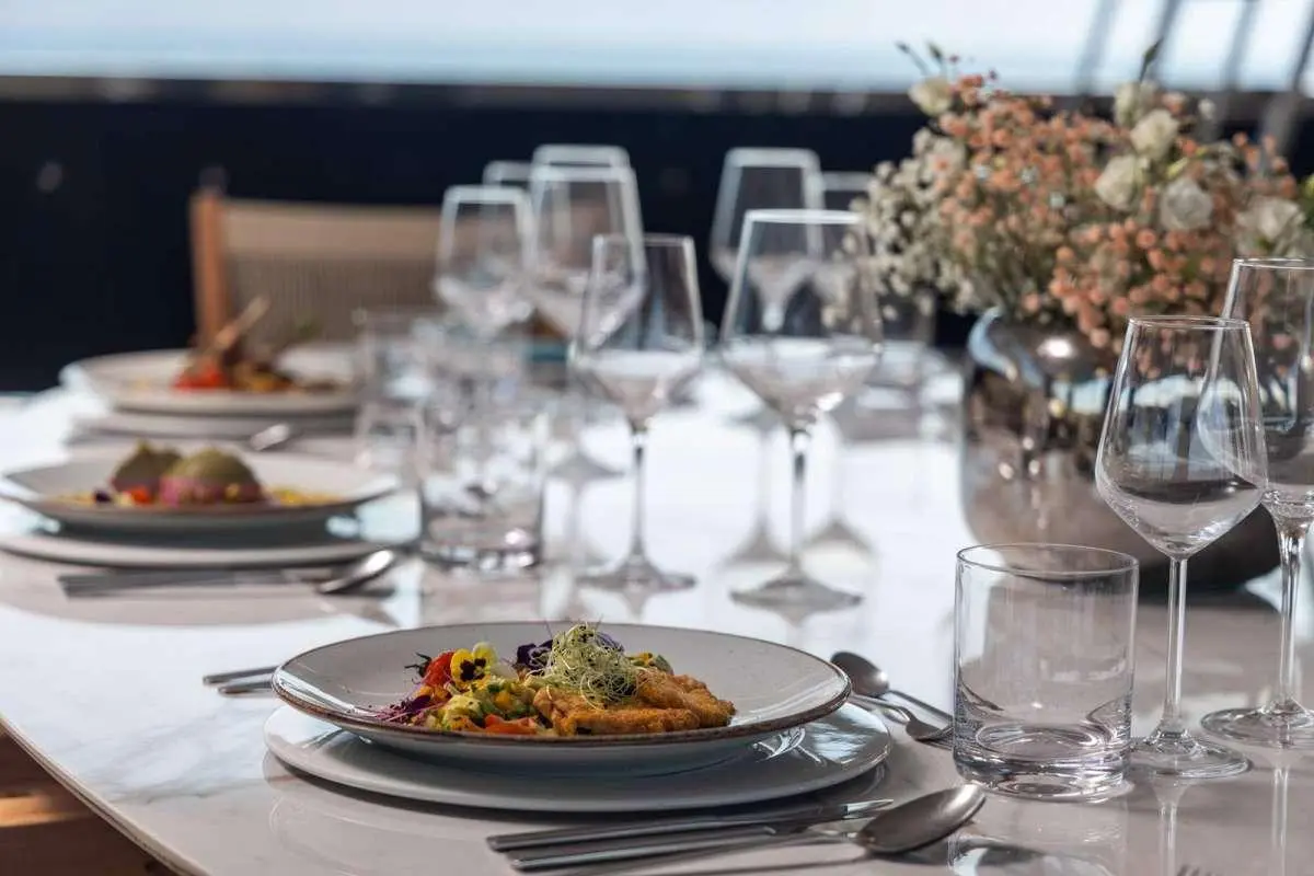 Olimp yacht table set with white napkins, china, glasses and plated dish